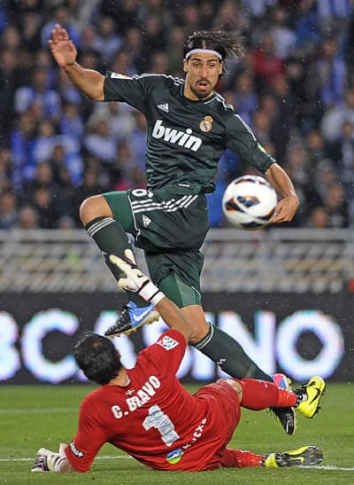 កីឡាករ Sami Khedira (ពីលើ) របស់ Real Madrid ស៊ុតបាល់ផុតដៃអ្នកចាំទី Claudio Bravo របស់ Sociedad អំឡុងការប្រកួតក្របខ័ណ្ឌ La Liga កាលពីថ្ងៃអាទិត្យ